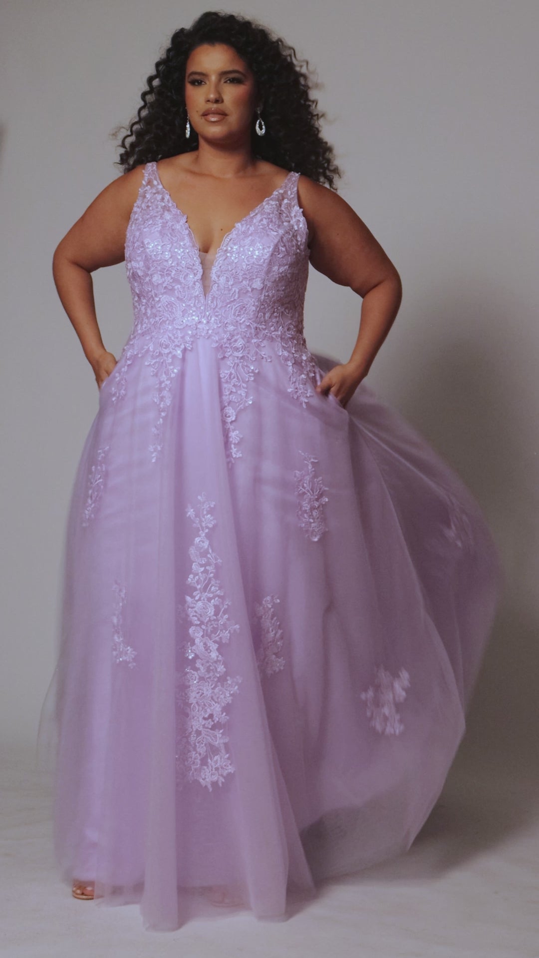 Plus size lace and tulle ball gown by Tease Prom.  Style TE2526 available in lilac purple or sage green.  Deep v-neckline with nude mesh insert. Wide straps and bodice fully covered with appliques.  Bodice is unlined but ships with optional lining panel.  Full A-line skirt with scattered lace appliques, pockets and chapel train. 