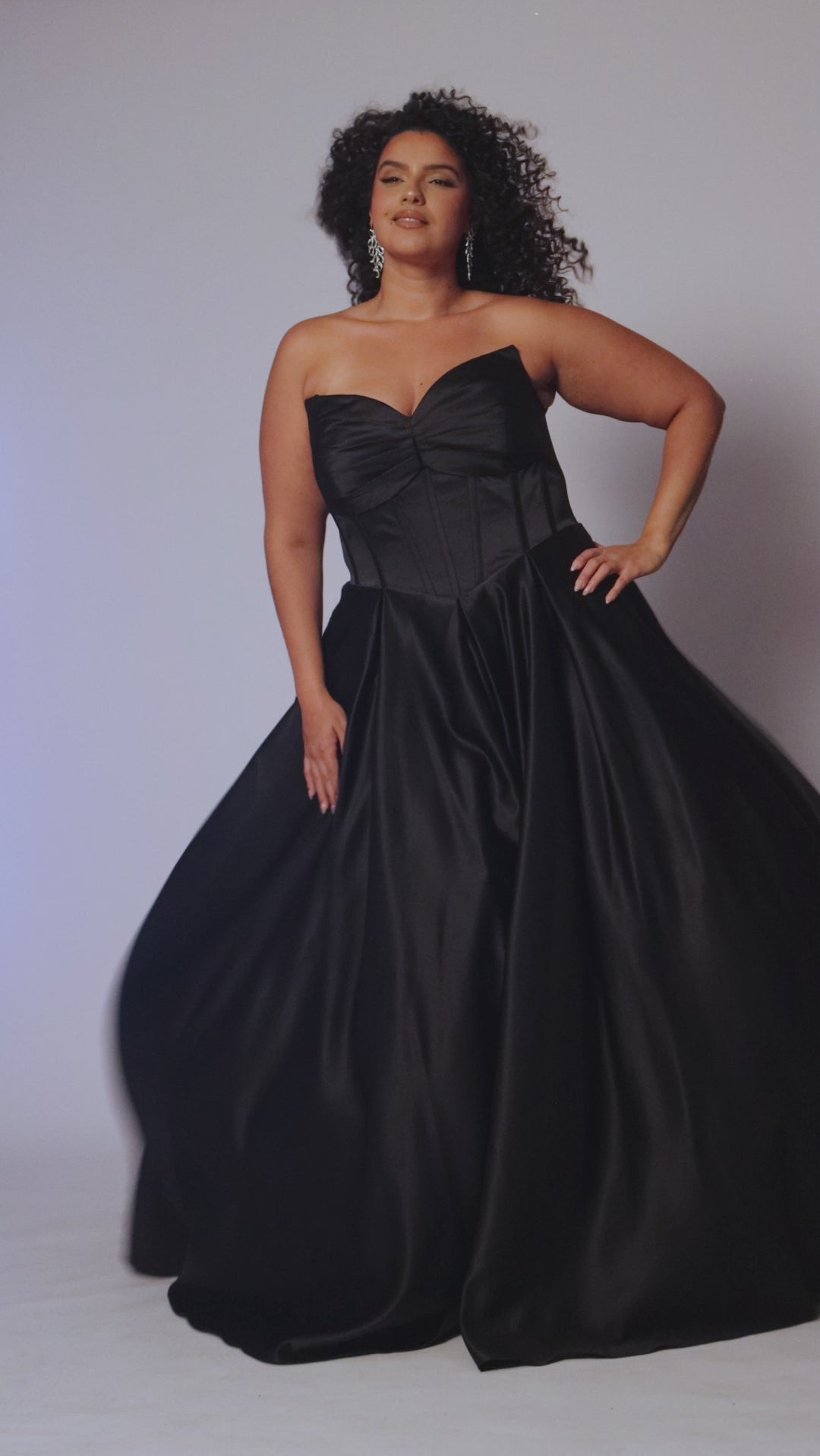 Long formal satin ballgown style SC7400 by Sydney's Closet. Available in sizes 14-32 in colors cobalt blue, onyx black and ruby red.  Pleated bodice with exposed boning, detachable pleated drape sleeves, basque waist and pockets.  