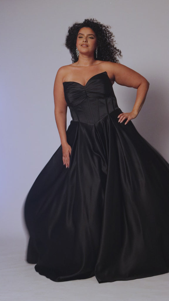 Long formal satin ballgown style SC7400 by Sydney's Closet. Available in sizes 14-32 in colors cobalt blue, onyx black and ruby red.  Pleated bodice with exposed boning, detachable pleated drape sleeves, basque waist and pockets.  