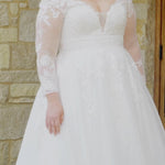 Plus-size bride wearing the Michelle Bridal MB2615 Jhoanna wedding gown featuring long lace appliqué sleeves, an illusion V-neckline with mesh insert, sparkle tulle A-line skirt, and a lace-accented waistband, available in Ivory and Ivory/Latte.