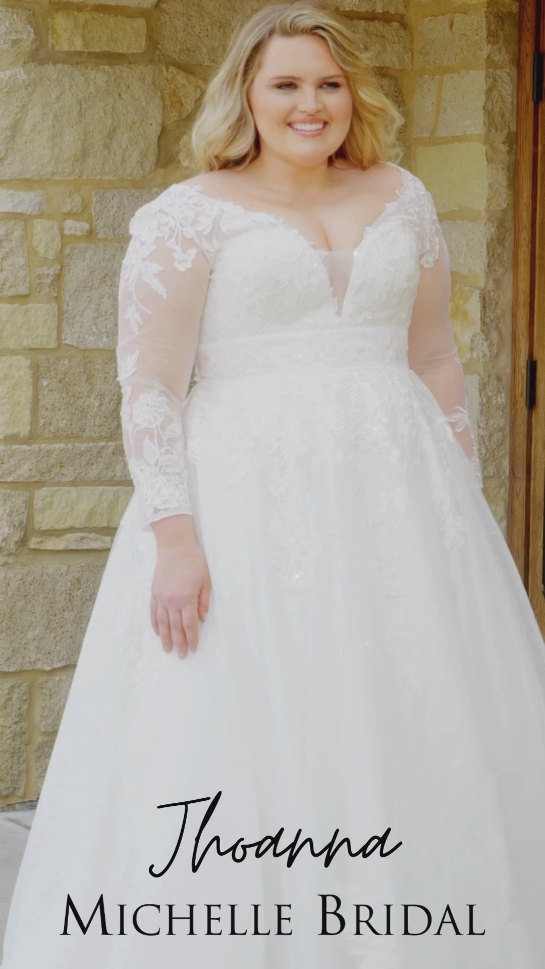 Plus-size bride wearing the Michelle Bridal MB2615 Jhoanna wedding gown featuring long lace appliqué sleeves, an illusion V-neckline with mesh insert, sparkle tulle A-line skirt, and a lace-accented waistband, available in Ivory and Ivory/Latte.