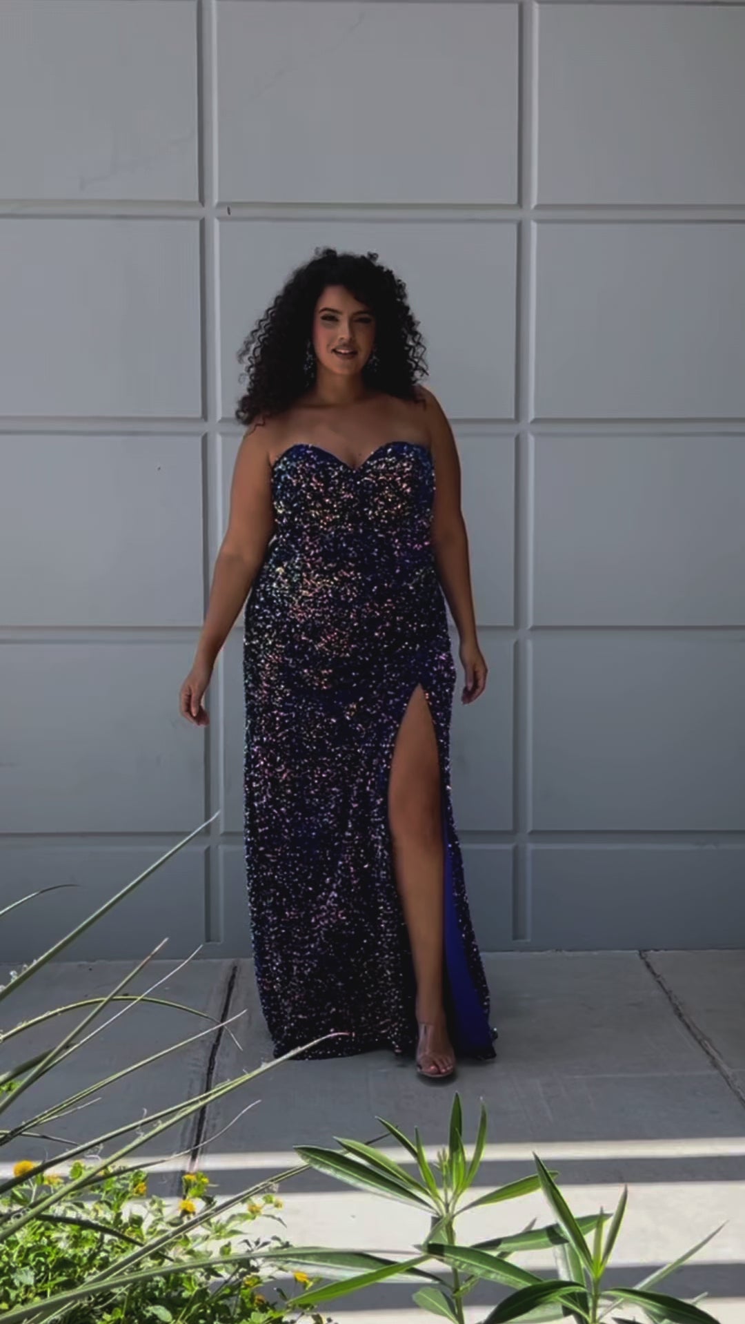 Fitted sequin velvet plus size formal gown with basque wqaist and ruched skirt with high slit. Available in cotton candy purple with pink accent, peacokc blue with green accent and royal blue in sizes 14-28 by Sydney's Closet. 