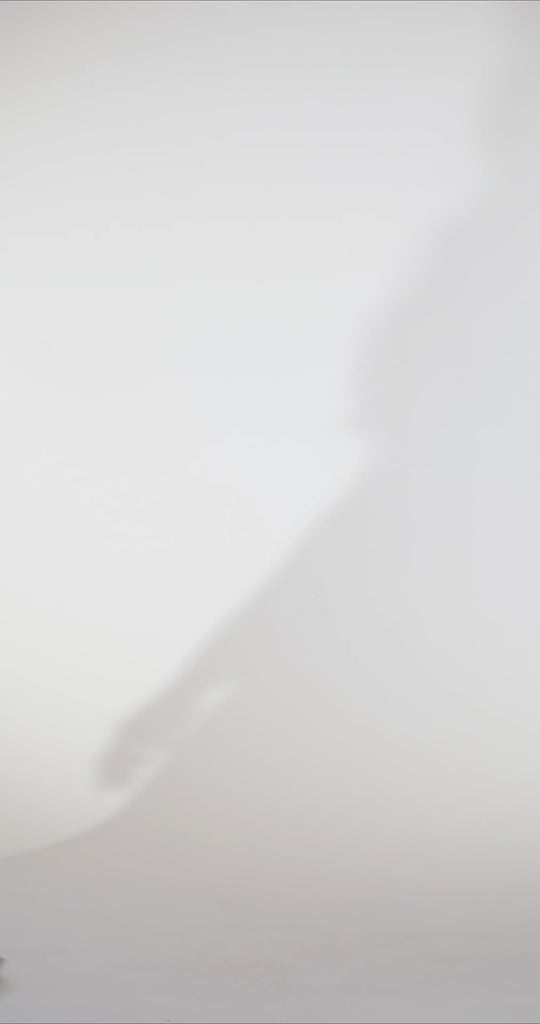 Woman models a black strapless satin gown with a draped neckline and thigh-high slit, turning to show the back before walking off screen.