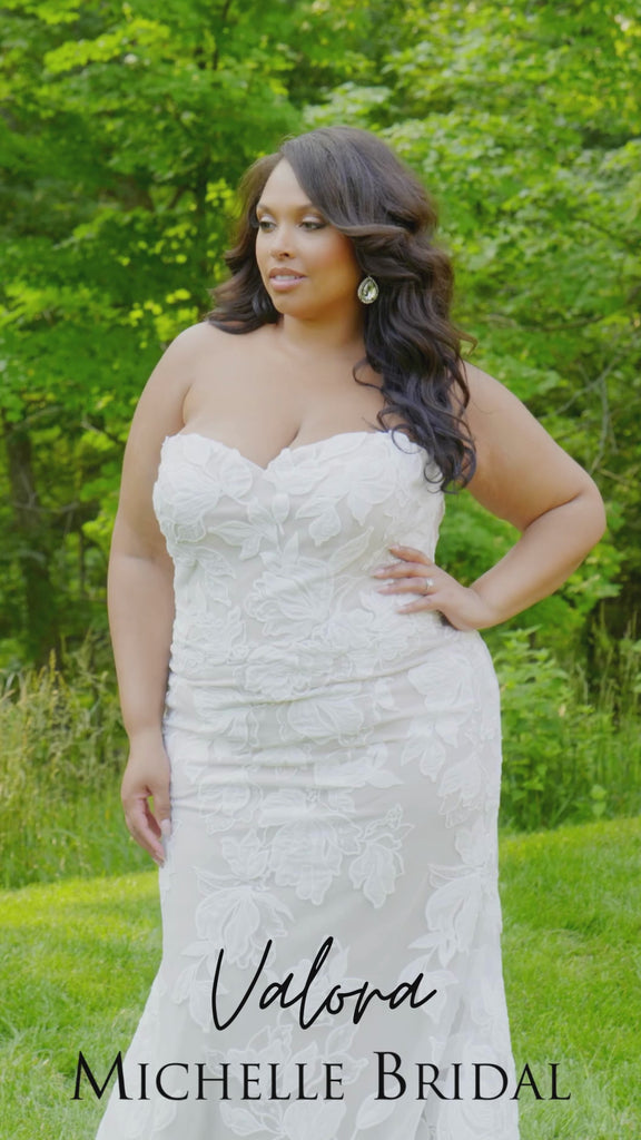 Plus-size bride modeling the MB2603 wedding gown by Michelle Bridal, showcasing a structured bodice and elegant flowing silhouette designed to flatter curves.