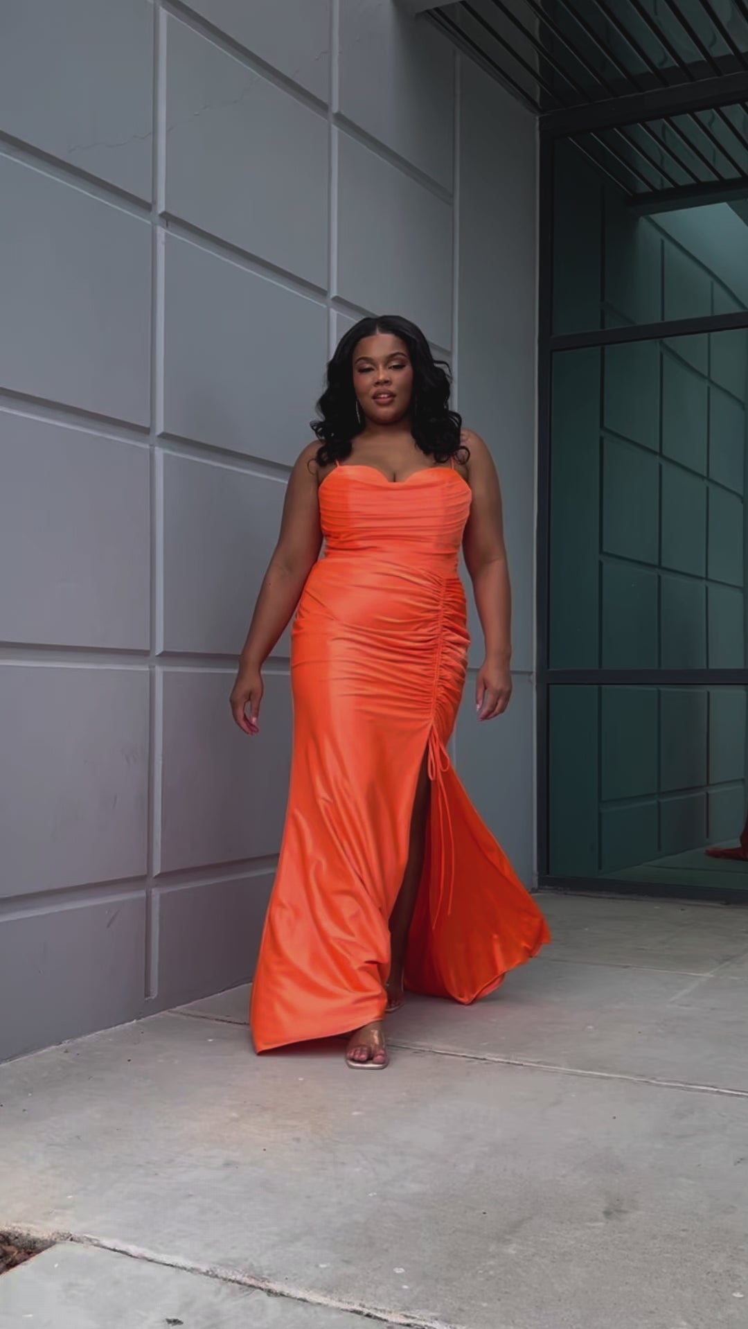 Slim fitted stretch satin plus size formal prom dress.  Pleated bodice, ruched skirt with gathered ties on slit, spaghetti straps and ruched back skirt with train.  Availablie in light blue, orange and lilac in sizes 14-24. Style SC7422 by Sydney's Closet. 