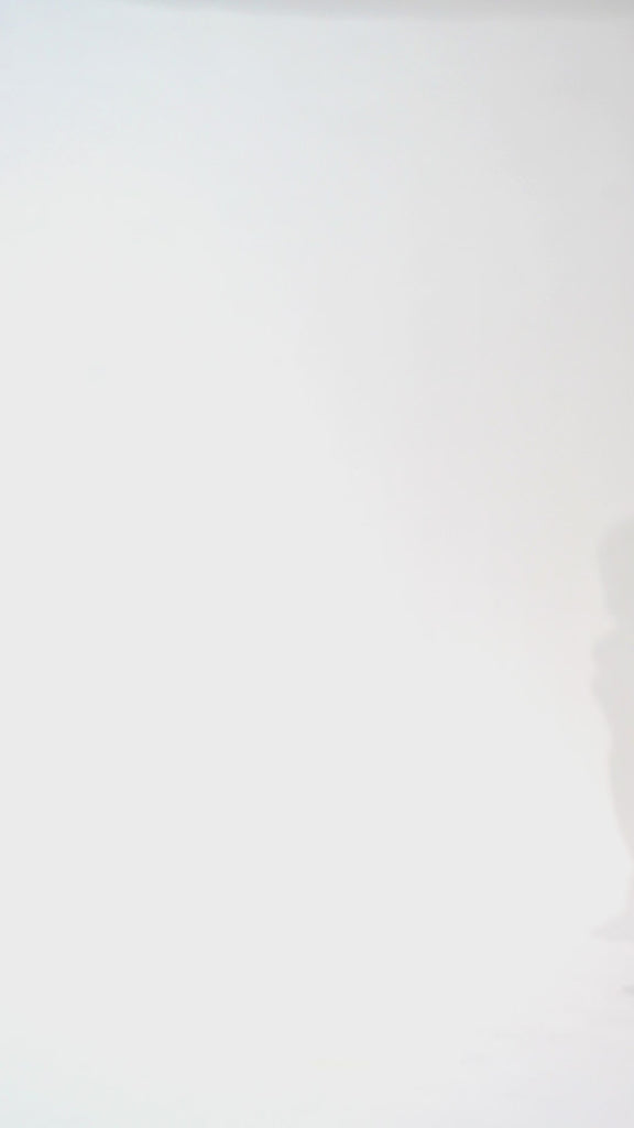 Woman models a strapless tea-length dress with a brown and black animal print and folded neckline detail, turning to show the back before walking off screen.