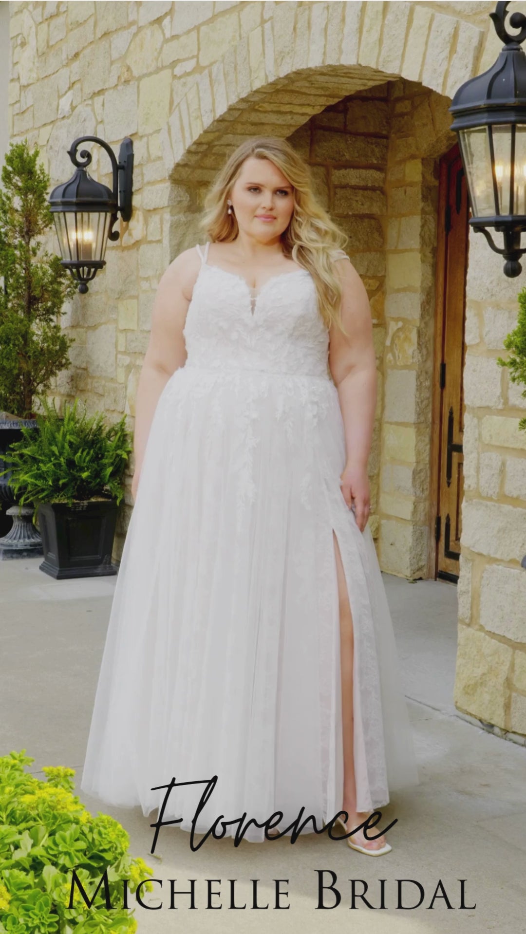 Plus-size bride wearing the Michelle Bridal MB2613 Florence A-line wedding gown with double beaded straps, a sweetheart neckline with nude mesh insert, floral appliqués and 3D organza flowers, and a Chantilly lace skirt with tulle overlay and a subtle slit.