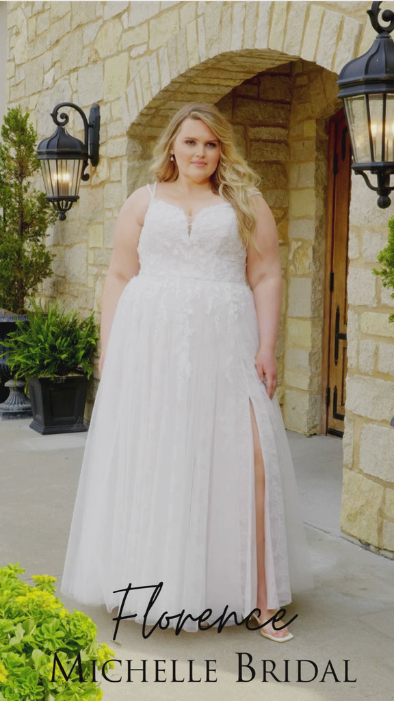 Plus-size bride wearing the Michelle Bridal MB2613 Florence A-line wedding gown with double beaded straps, a sweetheart neckline with nude mesh insert, floral appliqués and 3D organza flowers, and a Chantilly lace skirt with tulle overlay and a subtle slit.