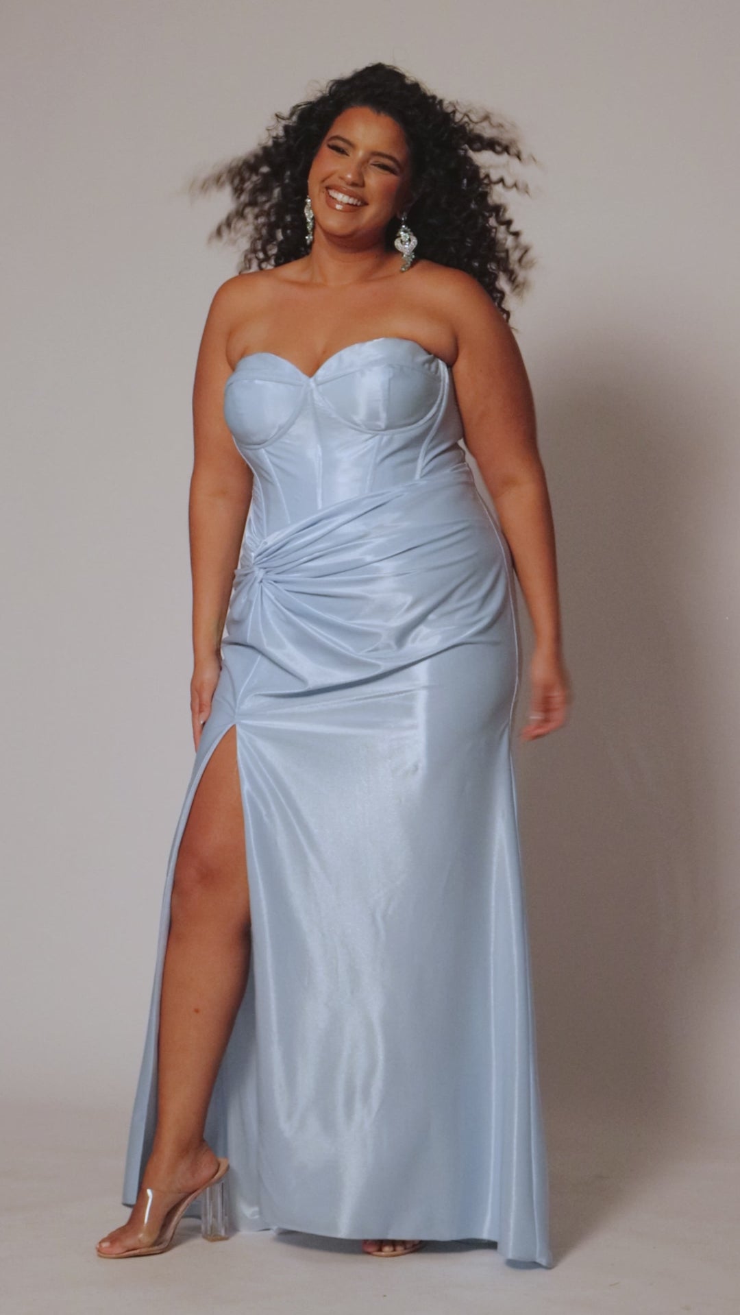 Sexy fitted pastel plus size prom dress by Tease Prom. Style TE2528. Strapless  bodice with asymmetrical basque waistline. Exposed corset boning and bustier bodice is fully lined.  Ruching and knot detail at the waistline and high slit with sweep train on a fitted skirt.  Tease Prom style TE2528 is available in lavender purple or sky blue in plus sizes 14-24. 