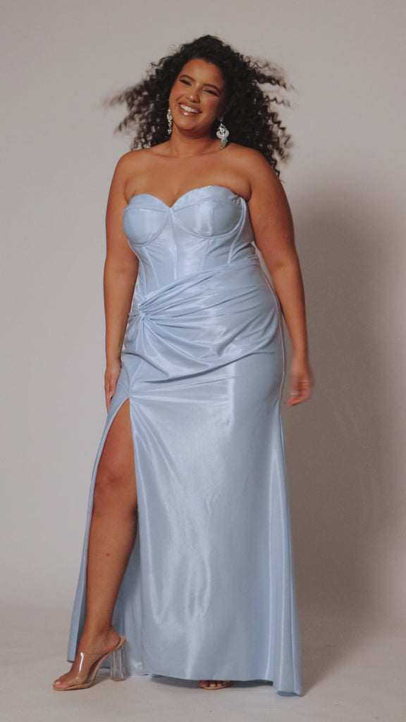 Sexy fitted pastel plus size prom dress by Tease Prom. Style TE2528. Strapless  bodice with assymetrical basque waistline. Exposed corset boning and bustier bodice is fully lined.  Ruchsing and knot detail at the waistline and high slit with sweep train on a fitted skirt.  Tease Prom style TE2528 is available in lavender purple or sky blue in plus sizes 14-24. 