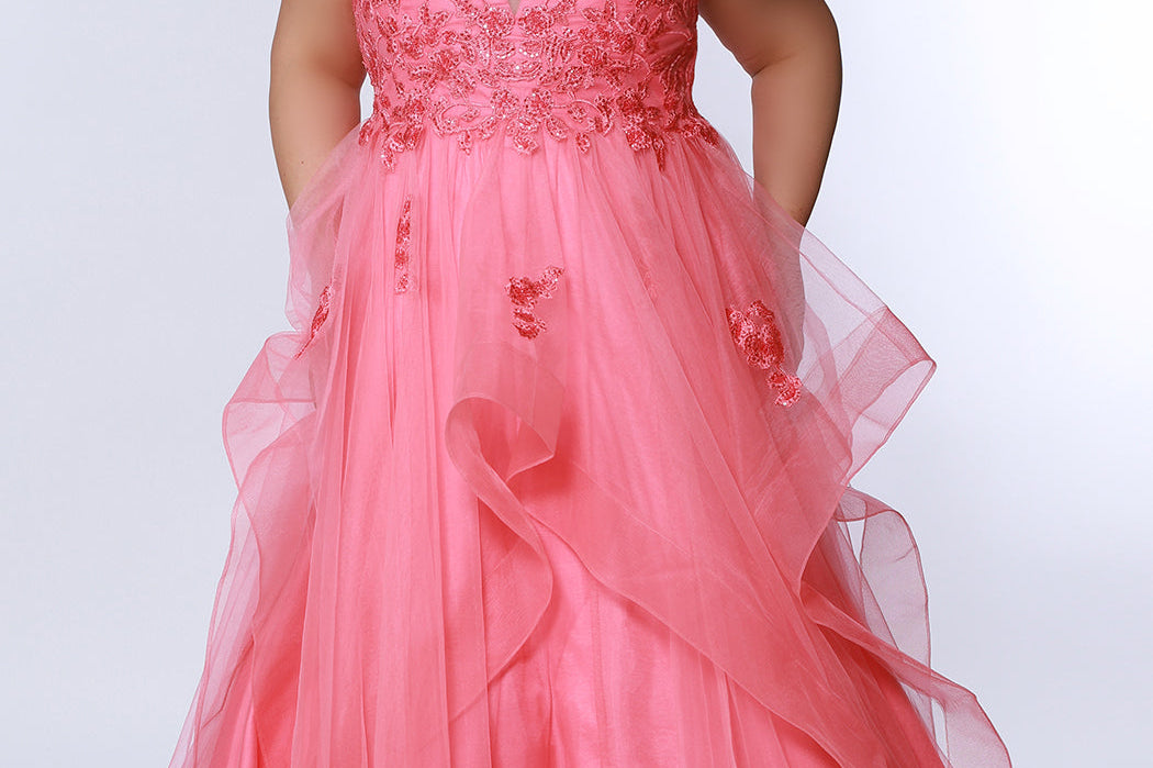 Sydney’s Closet SC7347 in Coral . Tulle ballgown with lace appliques on bodice. Offered in light blue, coral, light pink and lilac purple. Has a V-neckline, bra-friendly straps and a natural waistline. A tried tulle skirt with horsehair hem. Invisible back zipper