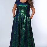 Sydney’s Closet SC7348 in peacock green. A-line silhouette with a scoop neckline and cap sleeves. Multidimensional sequins, offered in light blue, purple and peacock green. Has a natural waistline, A-line skirt with pockets, and a horsehair hem. 