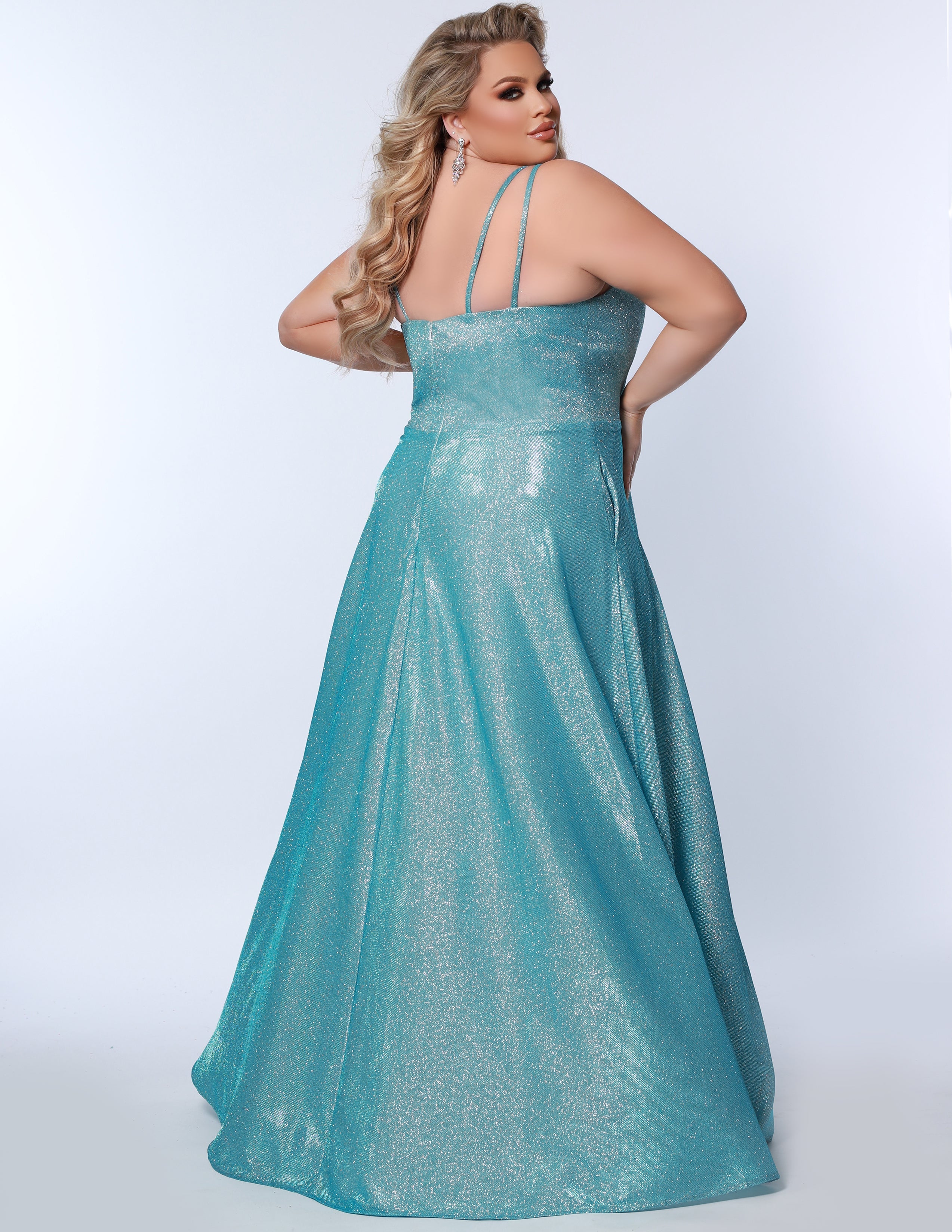 Sydney’s Closet SC7349 in aqua blue. Full A-line silhouette with a scoop neckline and double straps. Shimmer knit offered in pink, orange, purple and aqua blue. An A-line skirt with pockets and a left leg slit. Is fully lined, has a natural waist and a long invisible zipper.