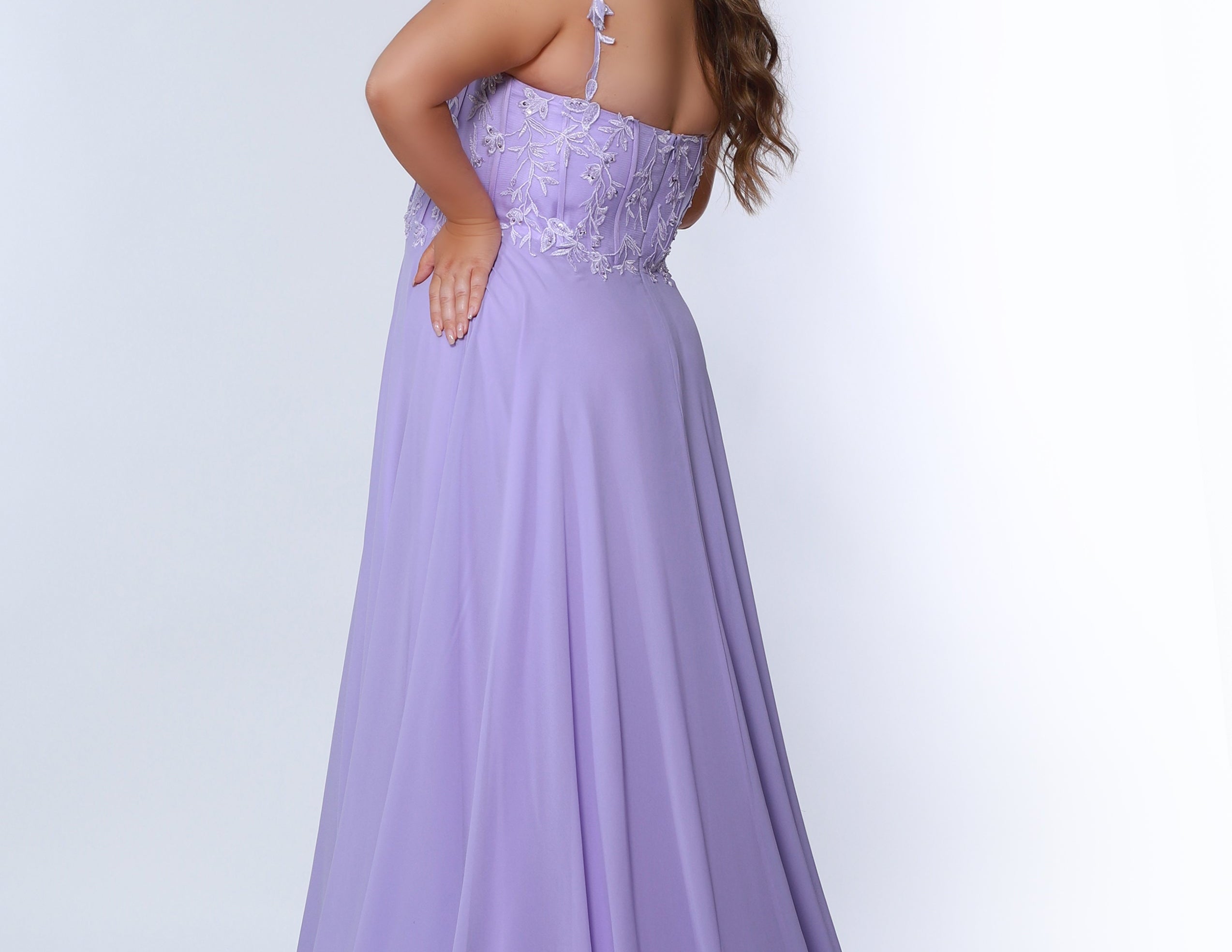 Sydney’s Closet SC7351 in light purple. Full A-line silhouette with a deep V-neckline and lace covered double straps. Chiffon, A-line skirt with a slit, and lace covered bodice with exposed boning. A natural waistline and partially lined bodice