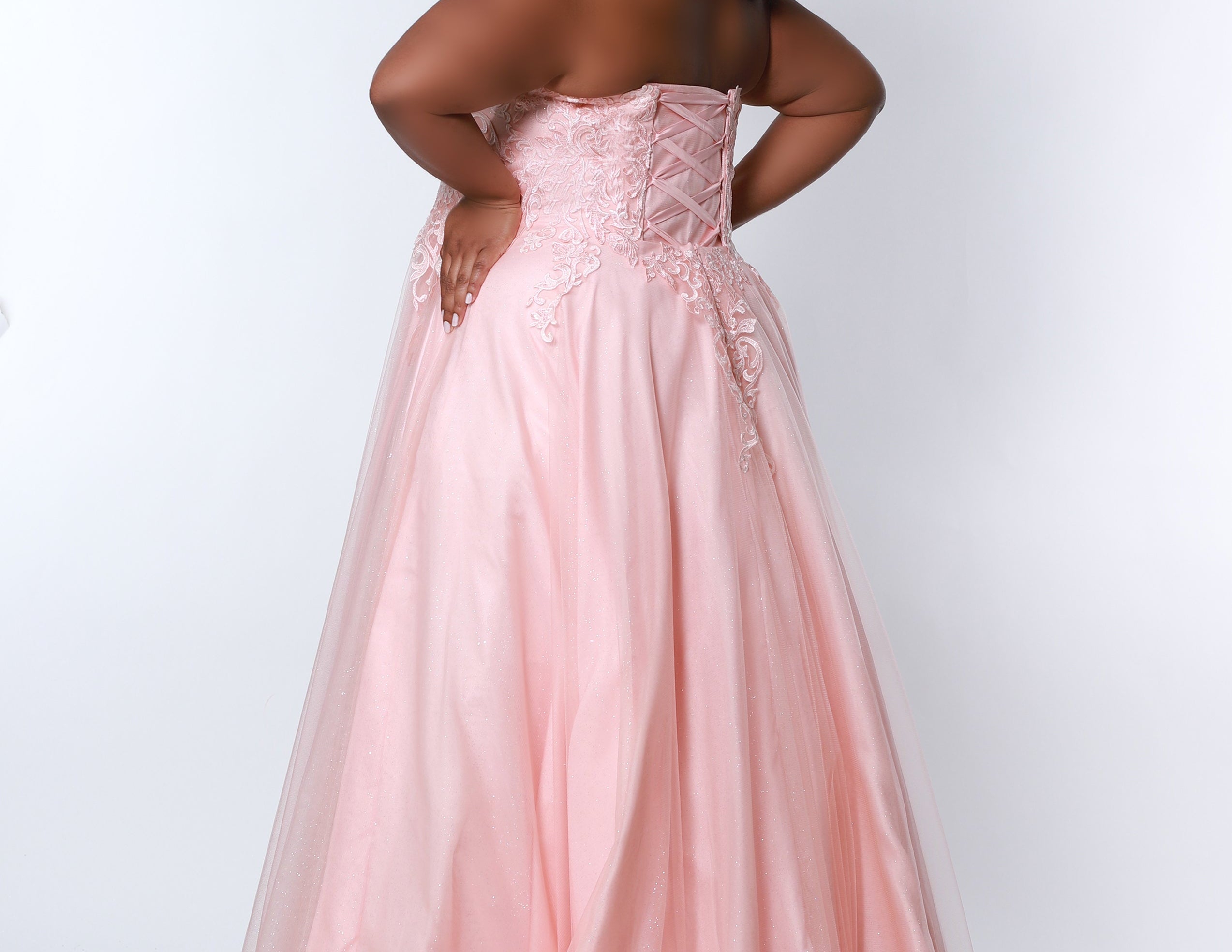 Sydney’s Closet SC7352 in peach pink . Full A-line silhouette with a halter neckline, a natural waistline, and an A-line skirt with crinoline, tulle and glitter tulle. Lace appliques cover the partially lined bodice and top of the skirt. Has a lace up back and modesty panel. Offered in  Ivory, Mint, Mocha, Orchid, and Peach.