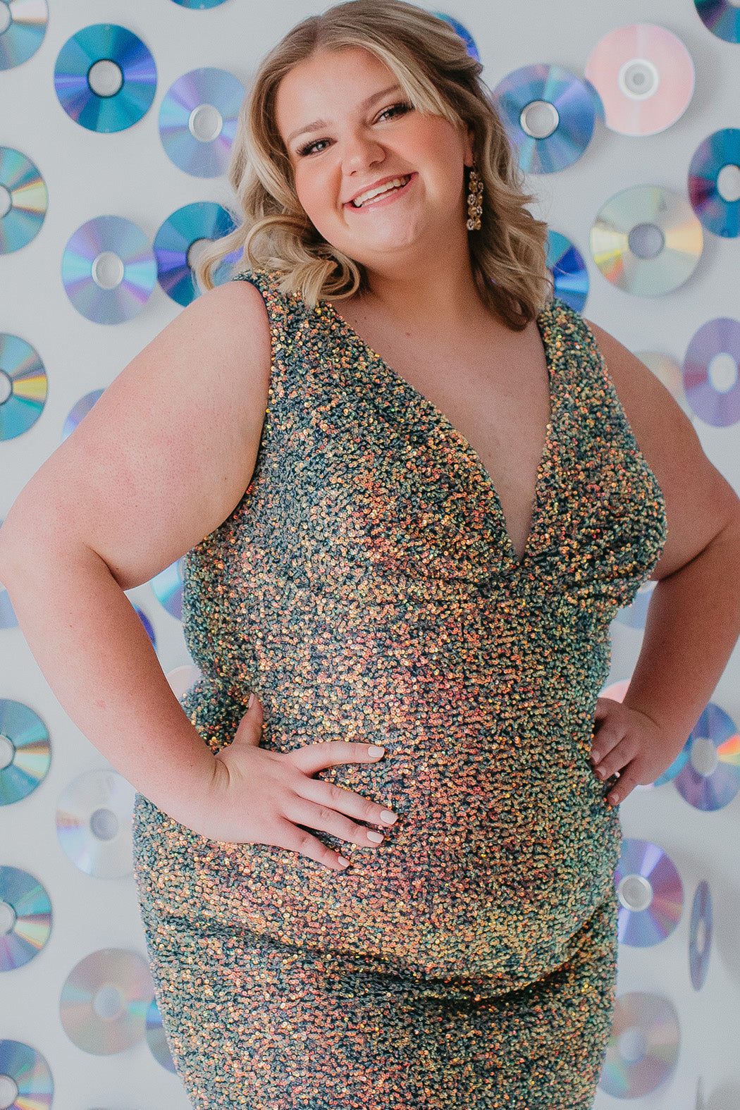 This is SC8110 in our Sydney's Closet Homecoming collection. This plus size party dress comes in blue, red, and green! This dress has bra friendly straps, empire waistline, and a v-neckline. This fitted all over sequin dress has a small slit above the right knee! This gown will catch the light for this homecoming season!