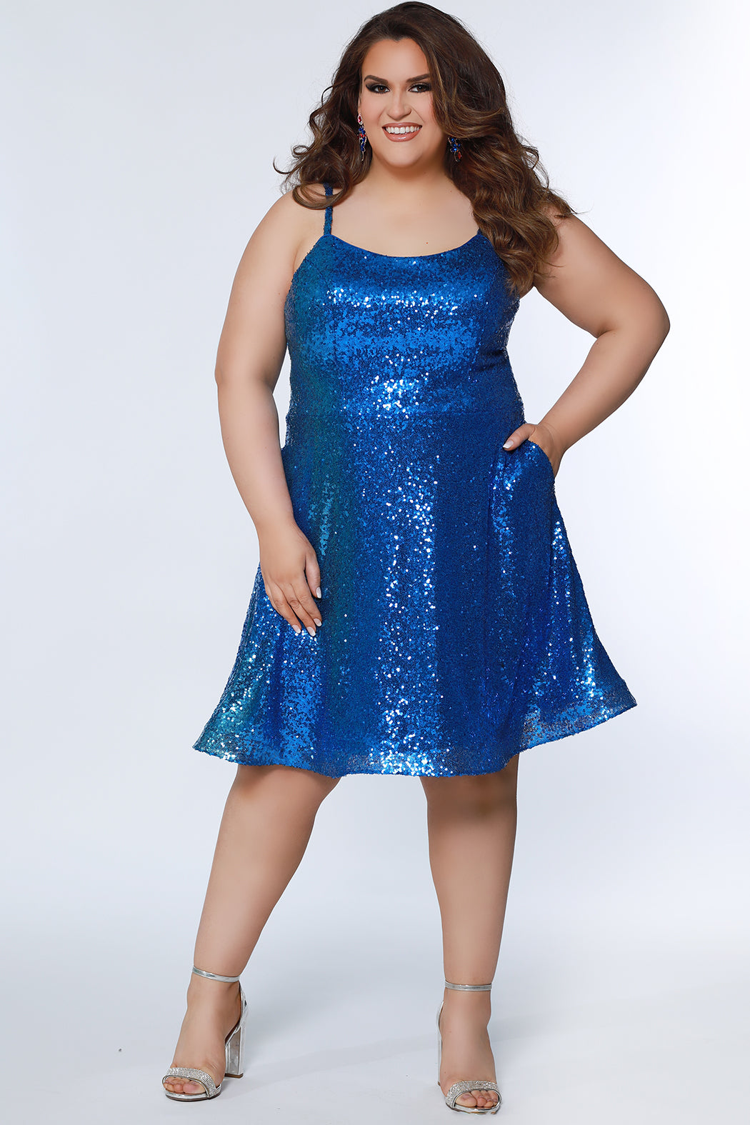 This is SC8122 in our Sydney's Closet Homecoming collection. This plus size party dress comes in white, red, blue, light blue, green, and purple! This dress has straps covered in sequins, a scoop neckline, and a natural waistline. This a-line all over sequins dress has a horsehair hem so that you can dance the night away! To make it even more spectacular, we have added pockets to make this the perfect dress for homecoming season!